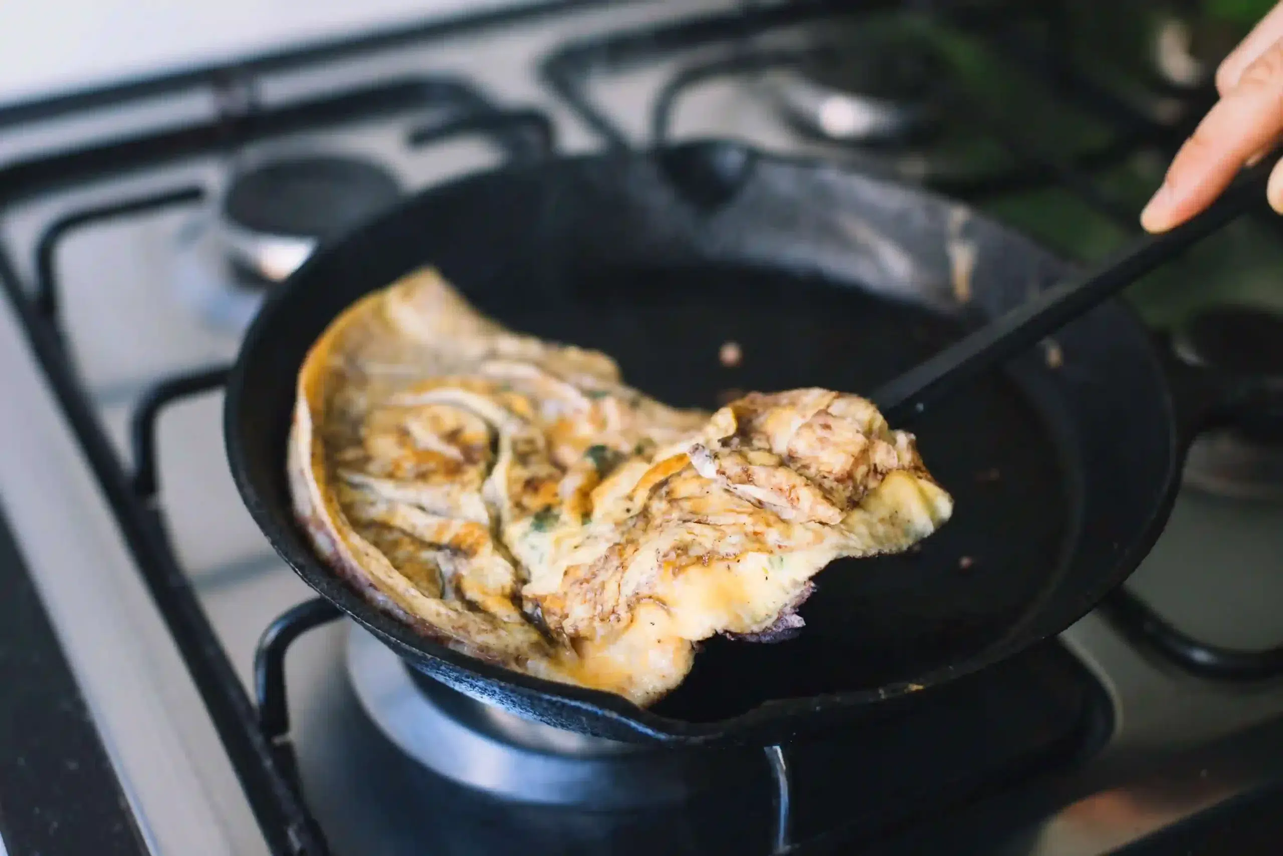 Cast iron skillet in use on kitchen stovetop showing even heat cooking performance